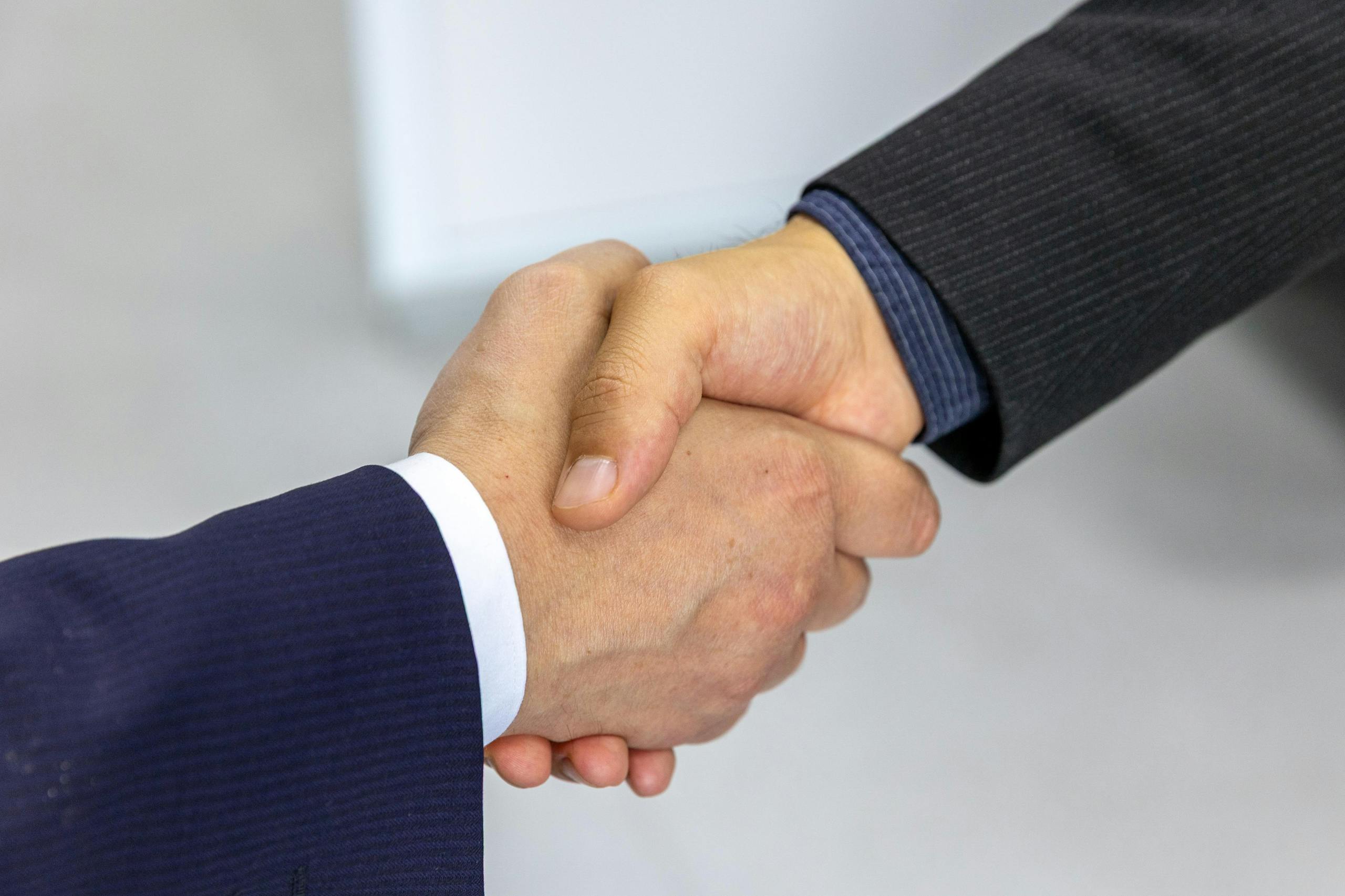 7 Reasons Why Choosing a Developer Feels Risky Close-up of two businessmen shaking hands, symbolizing agreement and partnership.
